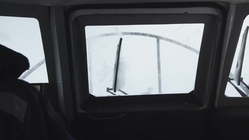 Man with coat drives boat throughice floes