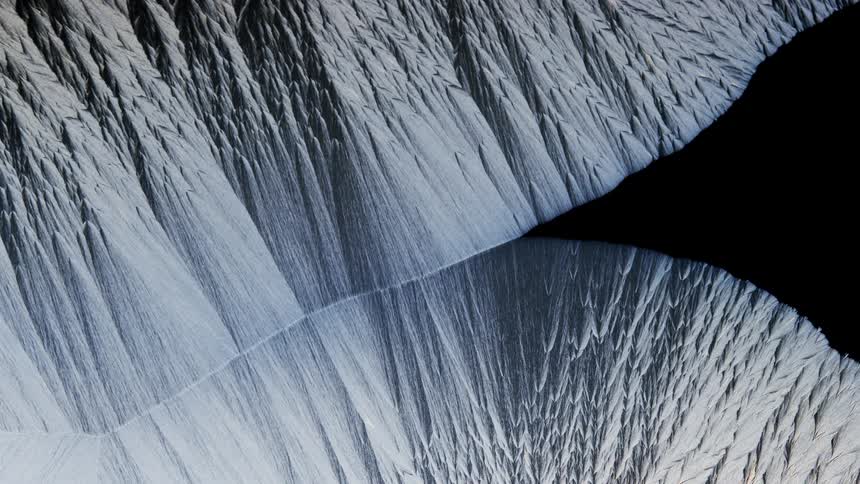 A textured white substance becomes more visible as the dark blackness moves away from the surface