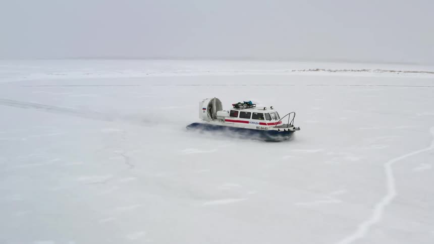 A large vehicle drives across a snow covered landscape