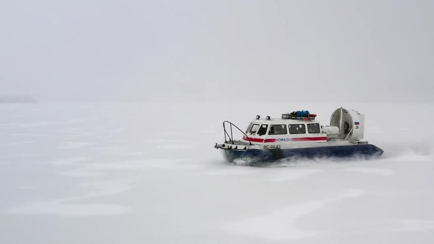Aerial view of man with coat driving boat through ice floes