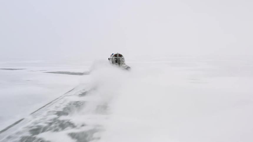 An air boat is traveling across the ice and leaves a trail in the snow behind it