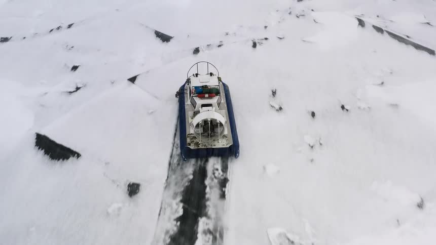A vehicle drives across a snow covered landscape