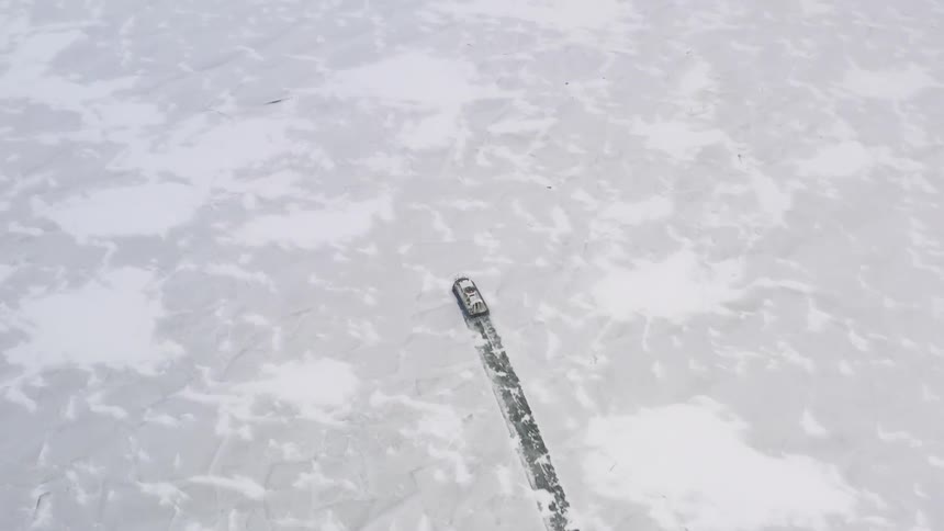 An airboat is gliding across the ice and leaving a trail in the snow behind it