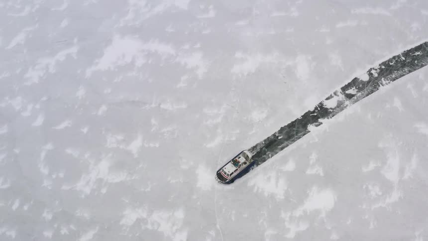 An airboat is gliding across the ice and leaving a trail in the snow