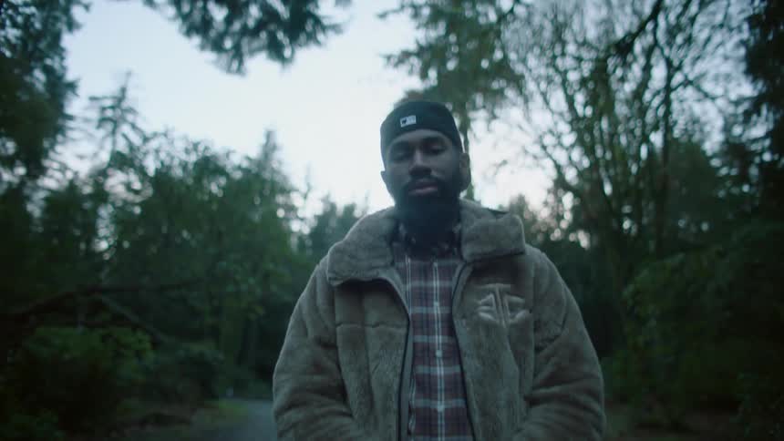 A man walking in a forest stops and slumps his shoulders
