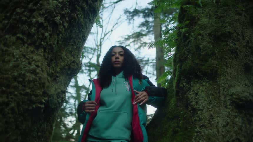 A teenage girl stands between two large trees