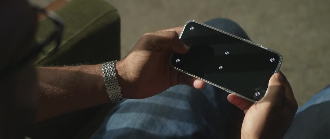 A young man is playing a game on his phone in the middle of the day time