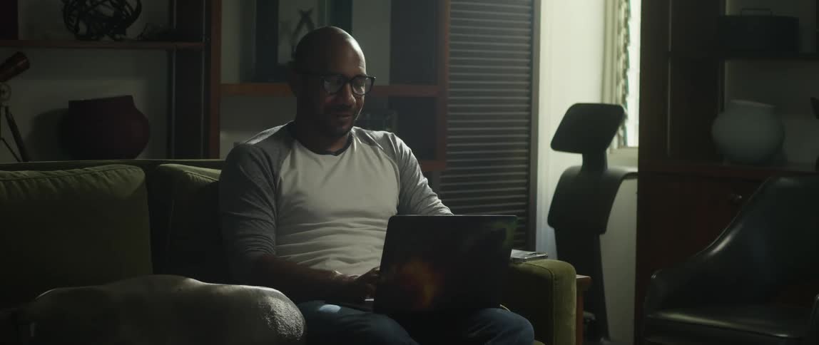 A man types on his laptop while sitting on the couch