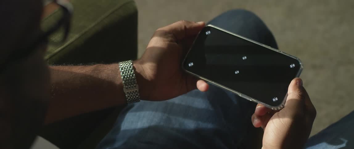 A man sits at home and looks at his cell phone