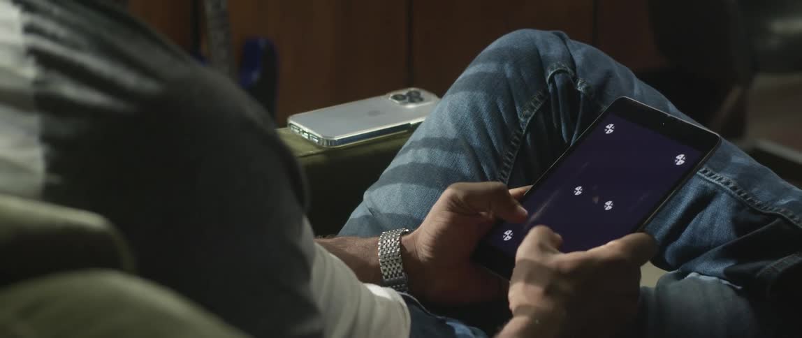 A man is sitting on a couch with a tablet