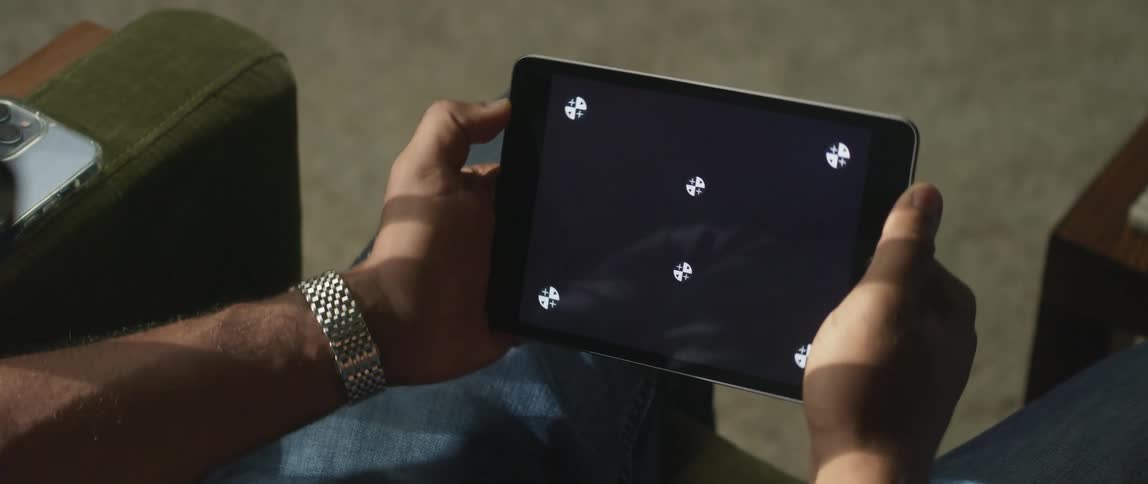 There is a man that is sitting down and playing a game on a device