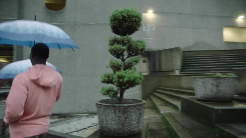 Man and woman walk down outdoor staircase toward the street on a raining day