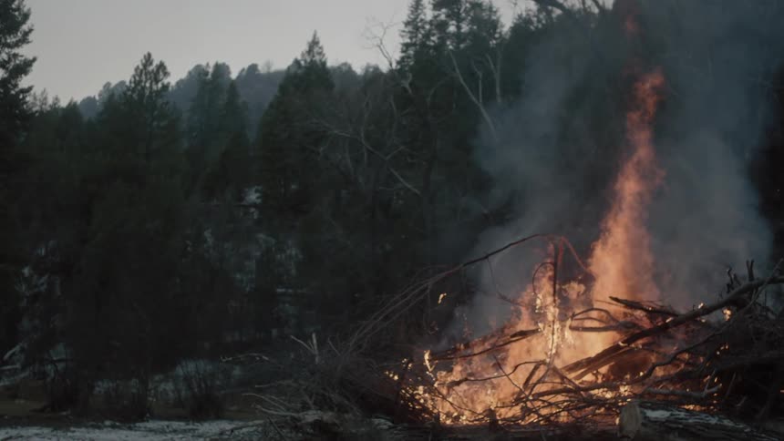 A large fire burns on a cloudy day