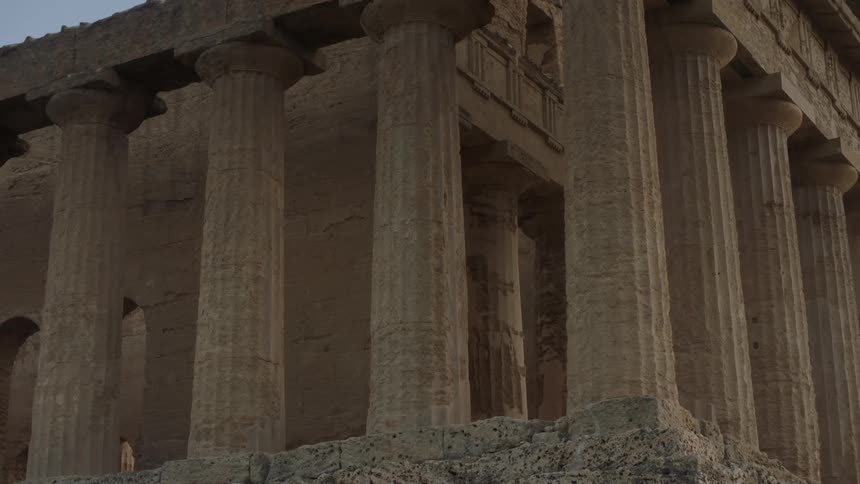 Pillars line this building as a woman walks past