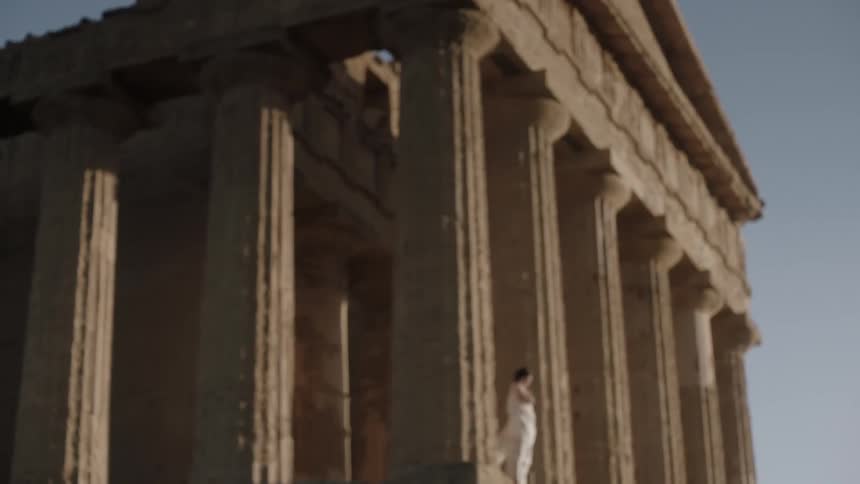 A woman standing between the columns of the acropolis