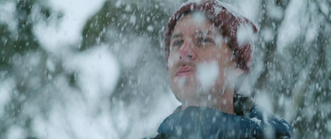 A man looks around at his surroundings while heavy snow falls around him
