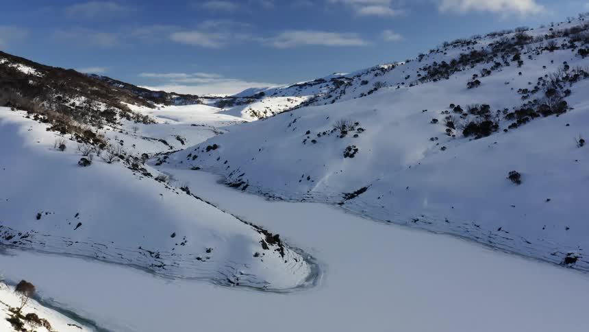 Aerial view of snowy mountains with frozen river