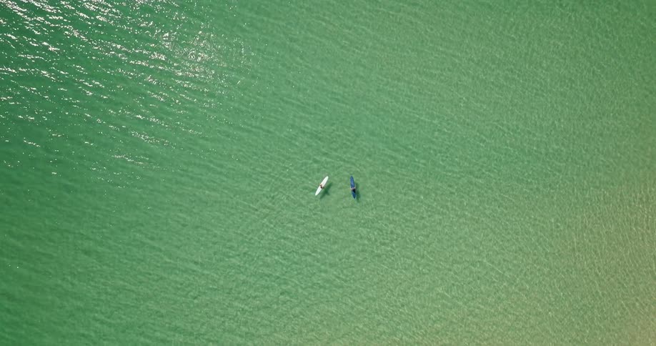 Two surfers sitting on their boards on clear sparkling ocean
