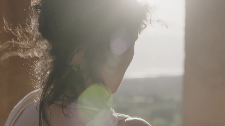 A woman in an ivory dress walks in the sunlight