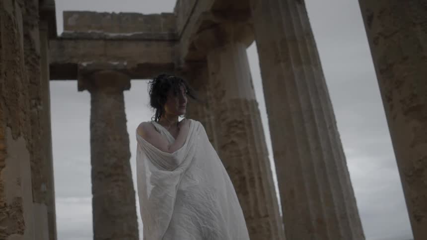 A woman wrapped in a white robe looks to the side