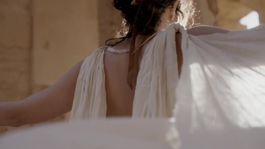 A woman wearing white robes stretches her arms out