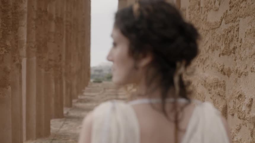 A woman standing next to a wall at the acropolis