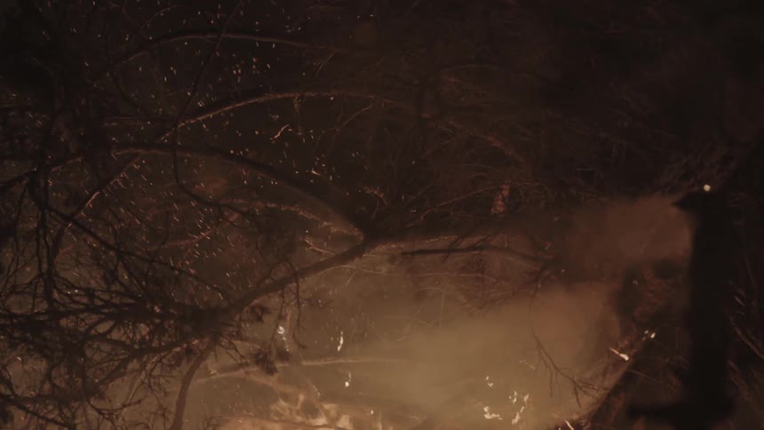 Burning embers floating through the air as a pile of tree branches burns