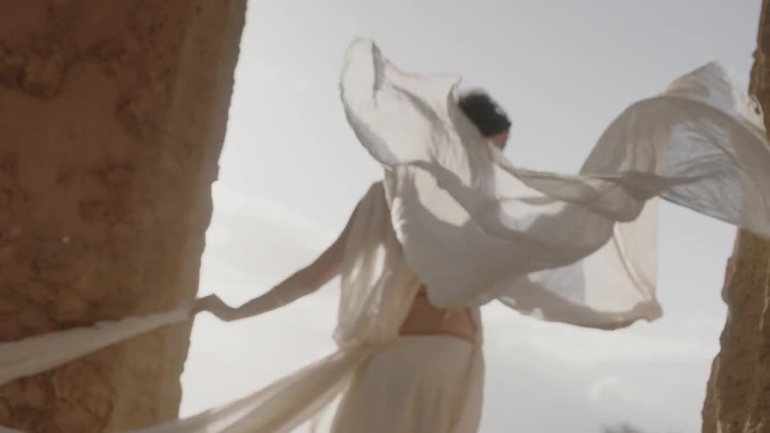 A woman's white robes blow in the wind