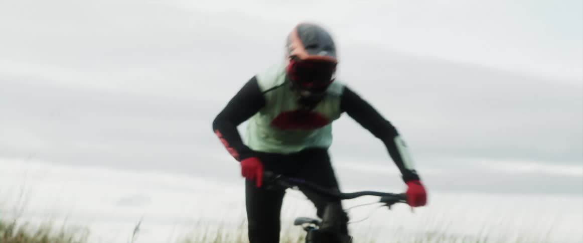 A bicyclist races through a field of tall weeds