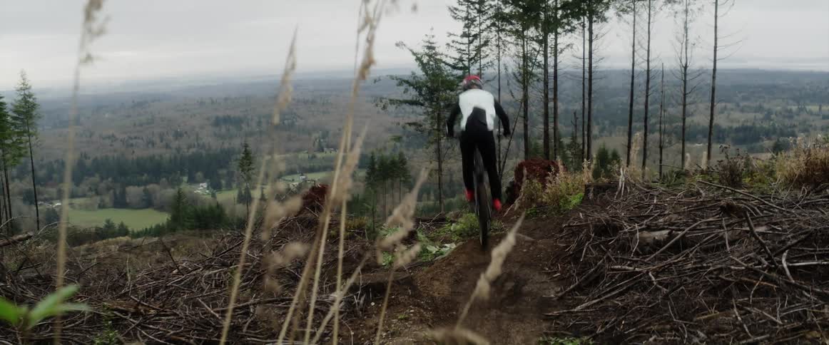 A mountain bike races down a dirt trail and jump
