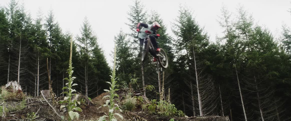 A mountain bike rider makes a jump off a mountain trail
