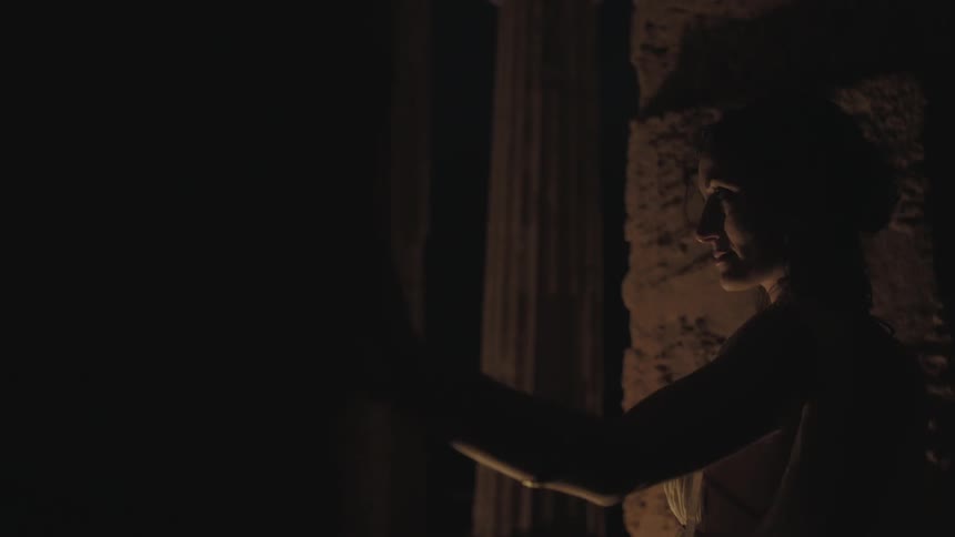 Woman standing by an old building at night