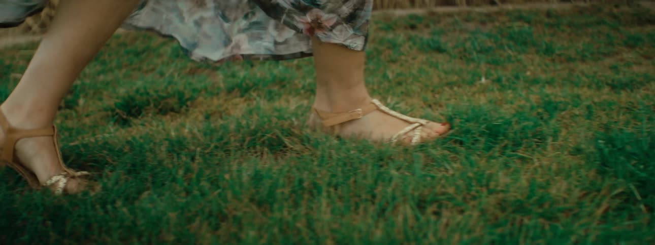 A woman walks through a field in a long dress