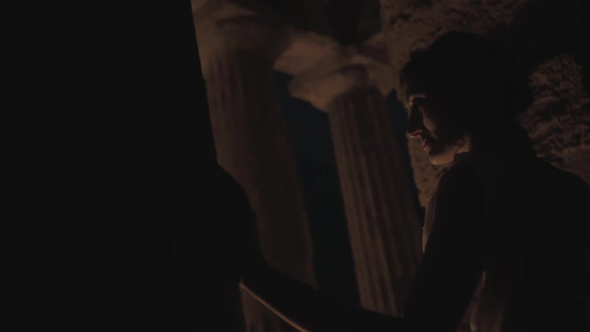 A woman leans against a wall at night