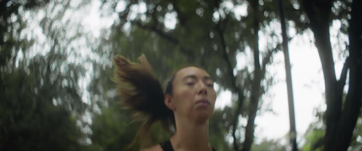 A womans hair whips back and forth as she jogs outside