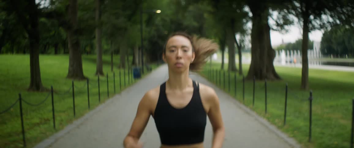A woman jogs down a path in a public park