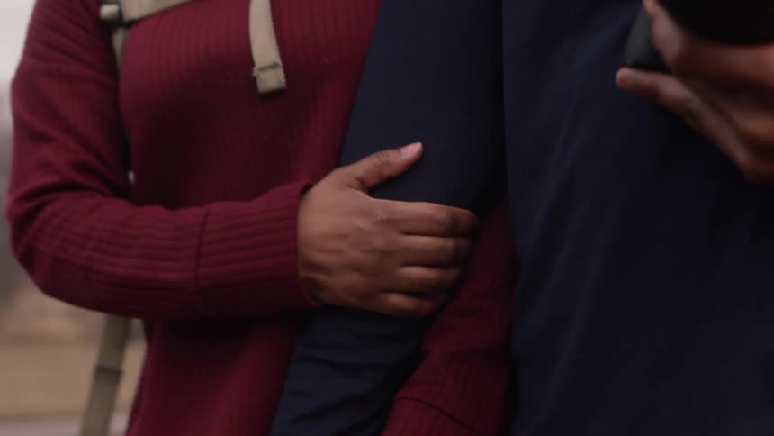 Two people walk arm in arm