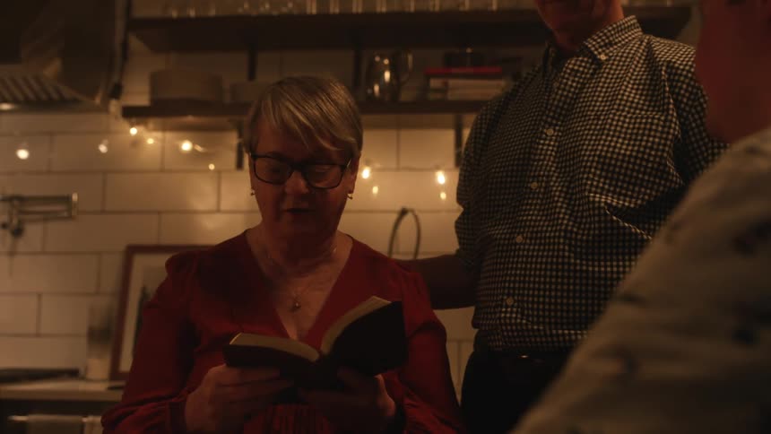 A family stands together as they read from the bible in their kitchen