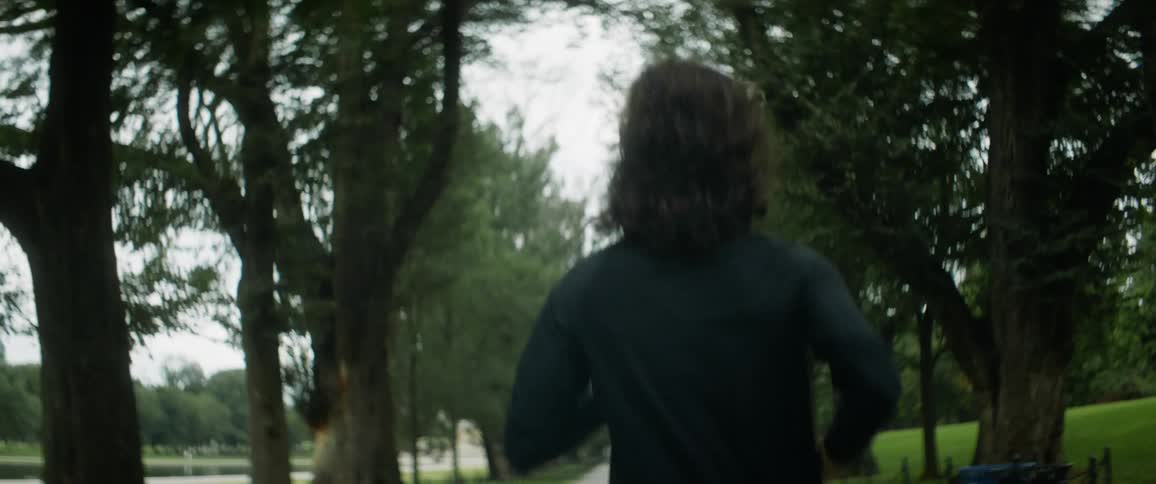 A woman runs down a tree lined park trail