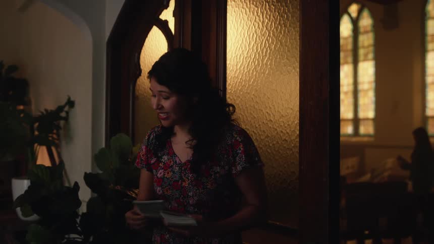 Woman standing on the entrance of a church greeting people and giving pamphlets
