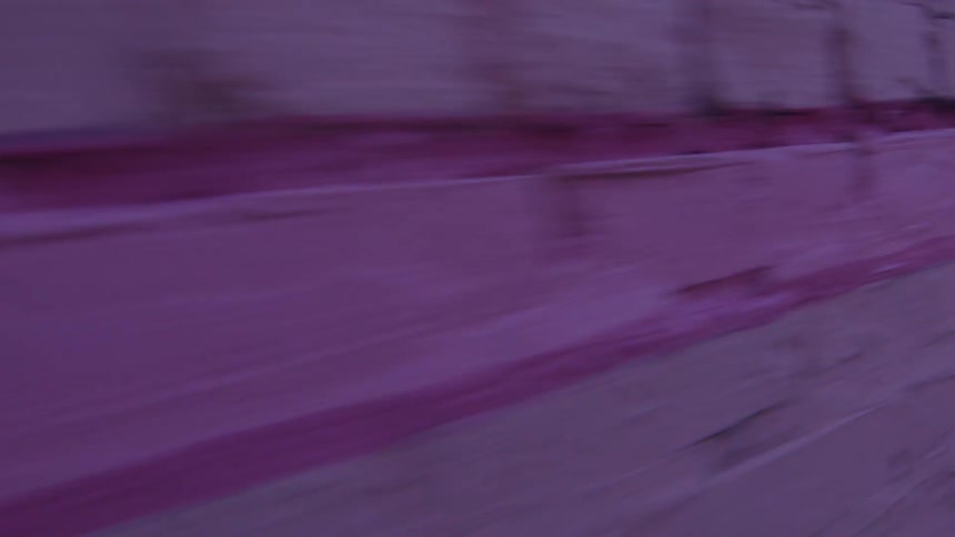 Vehicle passes by pink brick wall