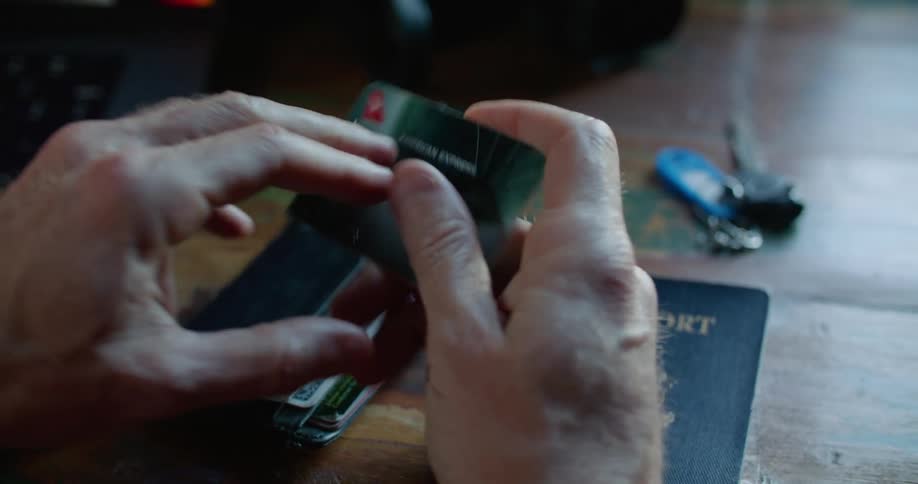A person turns around a credit card to read the numbers on the back to make an online purchase