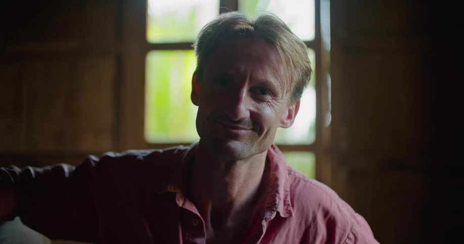 A man looking straight ahead smiles softly