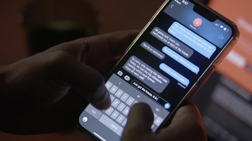 Person near laptop texts on their smatphone