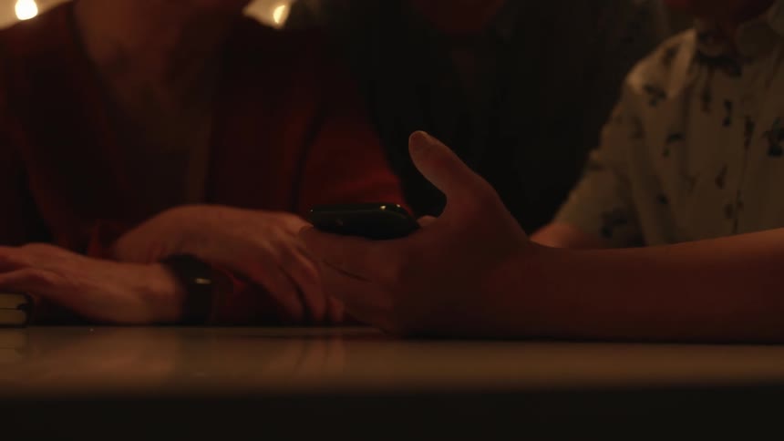 Family sitting around a table at home looking at a phone togheter