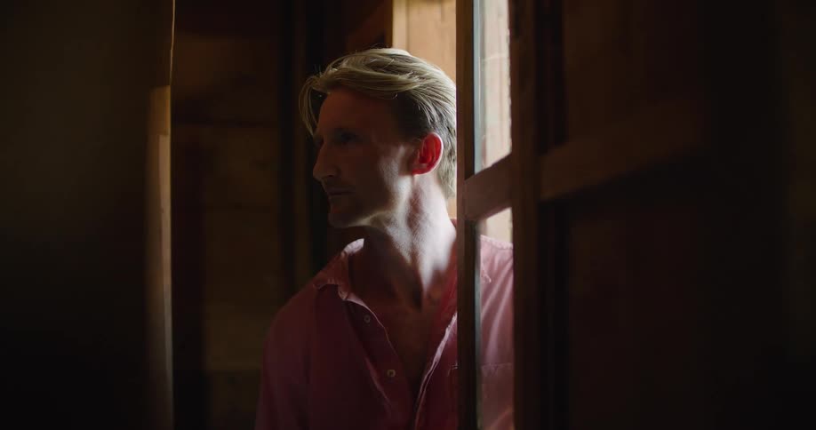 A man stands in the doorway of a house and looks around