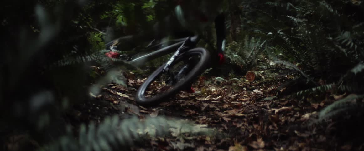 Cyclist with helmet jersey and pants takes bend on forest track