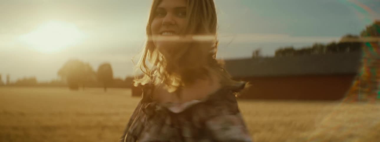 A woman spins in circles and laughs in a field