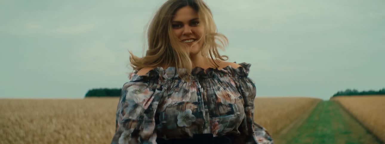A woman is walking outdoors in a field