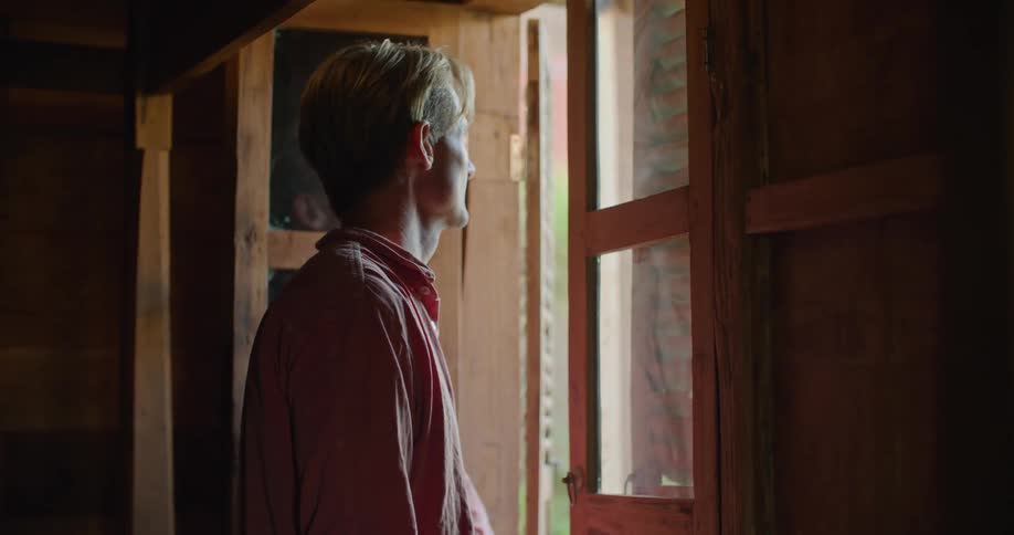 Man opens shutter and stands looking out